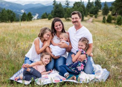 Littleton family photographer local affordable Mt. Falcon park in Colorado with a mountain view four girls sisters photography field summer mother father parenthood baby girl antique quilt