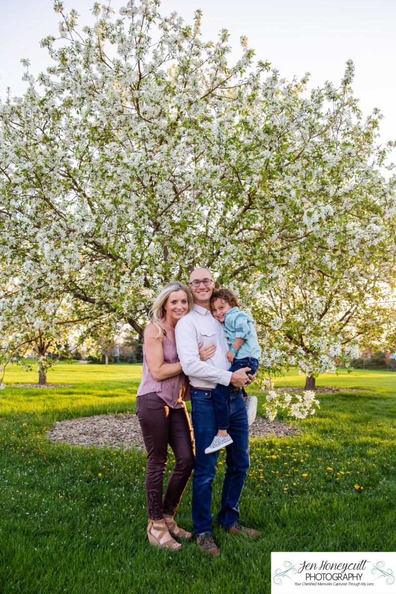 Littleton family photographer spring in Colorado crab apple tree blossoms pink and white trees little boy mother father son golden hour sunset light